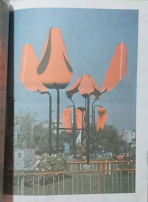 A steel memorial sculpture at Jaleh Square in Tehran displaying three tulips in the flowering cycle stages: in the bud, blooming, and withered.