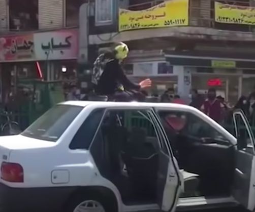 Screenshot from a User Generated Content video of a woman dancing on a car roof in Tehran, 2021. — © In Field Journal 21, Spring 2022.